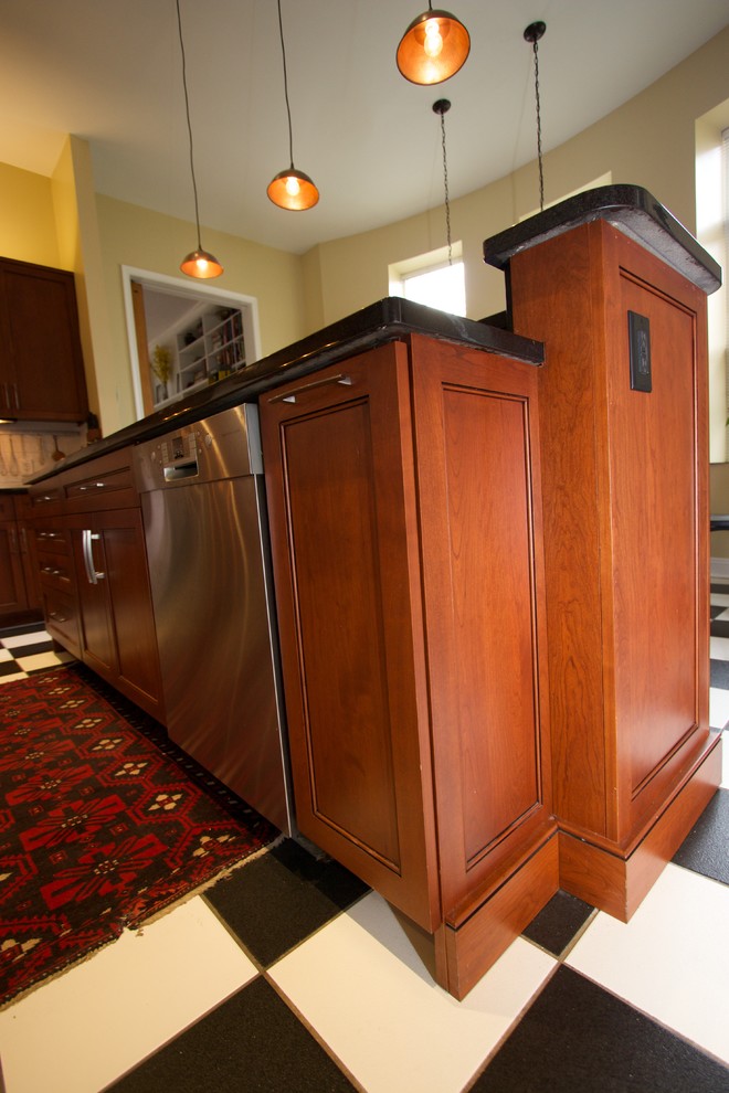 Exemple d'une cuisine américaine chic en U et bois brun avec un placard avec porte à panneau encastré, un plan de travail en granite, un électroménager en acier inoxydable et îlot.