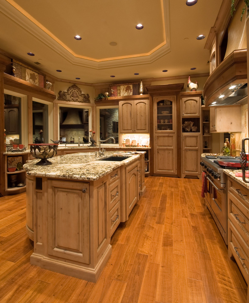 Inredning av ett lantligt avskilt, mycket stort u-kök, med en undermonterad diskho, luckor med upphöjd panel, skåp i ljust trä, granitbänkskiva, beige stänkskydd, stänkskydd i stenkakel, integrerade vitvaror, mellanmörkt trägolv, flera köksöar och brunt golv