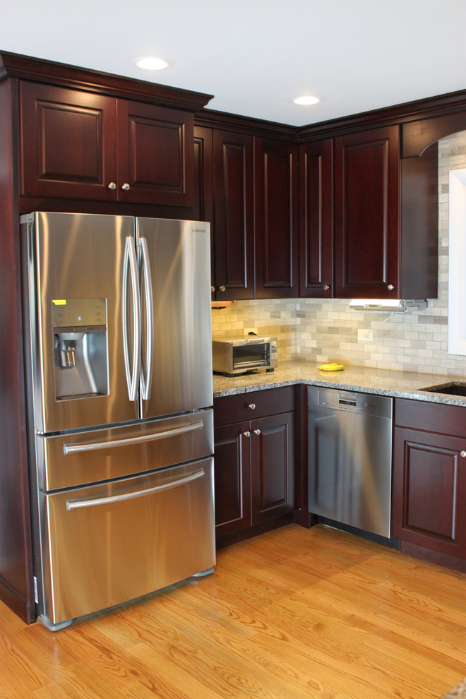 Example of a mid-sized transitional u-shaped laminate floor eat-in kitchen design in Other with an undermount sink, raised-panel cabinets, dark wood cabinets, quartz countertops, gray backsplash, porcelain backsplash, stainless steel appliances and no island