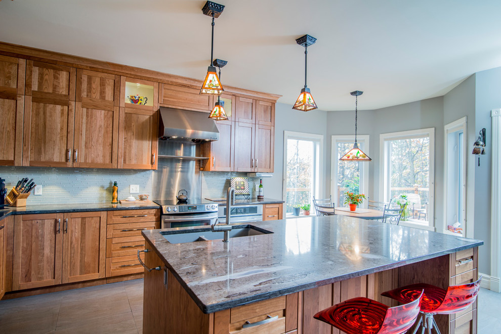 Example of a classic l-shaped eat-in kitchen design in Montreal with an undermount sink, shaker cabinets, medium tone wood cabinets, granite countertops, white backsplash and stainless steel appliances