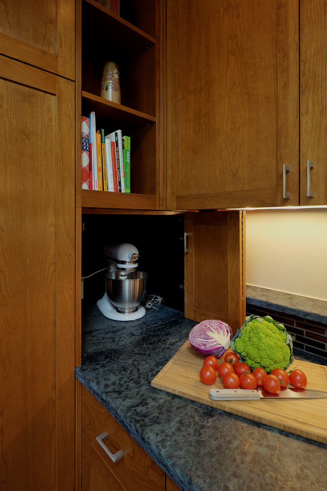 Exempel på ett klassiskt kök, med en enkel diskho, släta luckor, skåp i mellenmörkt trä, bänkskiva i täljsten, grått stänkskydd, stänkskydd i sten, rostfria vitvaror, klinkergolv i porslin och grått golv