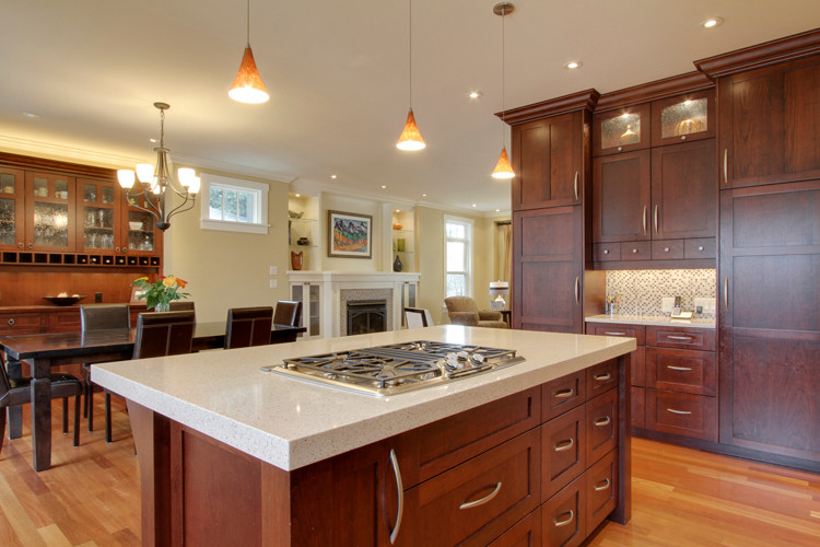 Example of a large classic u-shaped medium tone wood floor eat-in kitchen design in Calgary with an undermount sink, shaker cabinets, medium tone wood cabinets, quartz countertops, multicolored backsplash, ceramic backsplash, stainless steel appliances and an island
