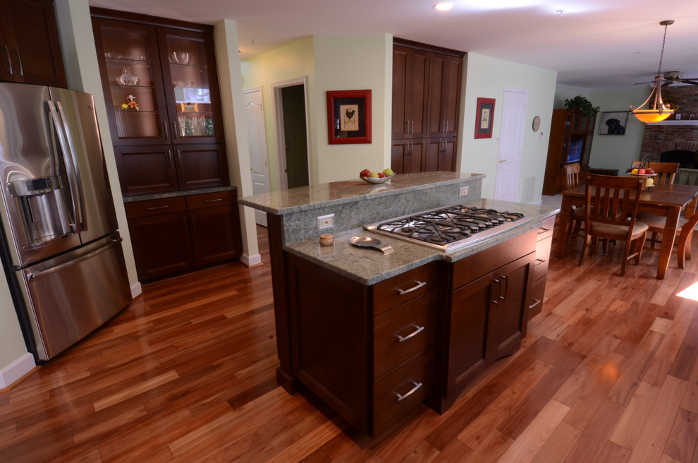 Photo of a medium sized classic l-shaped kitchen/diner in Baltimore with shaker cabinets, dark wood cabinets, granite worktops, stainless steel appliances, dark hardwood flooring, an island and brown floors.