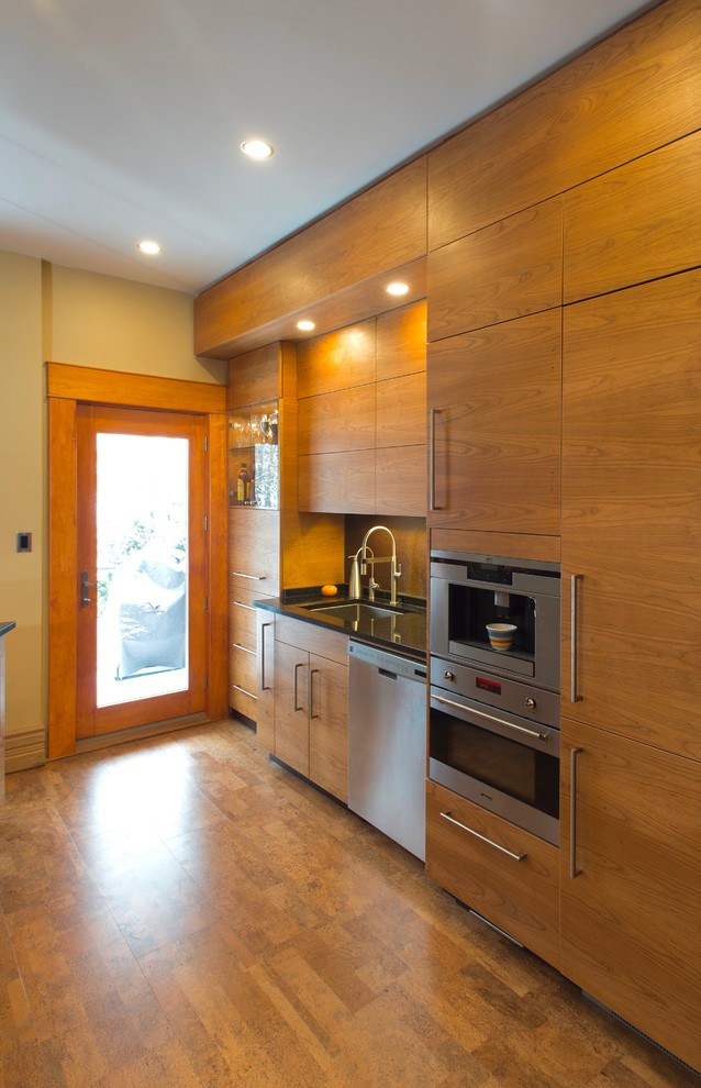 Inspiration pour une petite cuisine parallèle minimaliste en bois brun avec un évier encastré, un placard à porte plane, un plan de travail en granite, une crédence métallisée, un électroménager en acier inoxydable et un sol en liège.