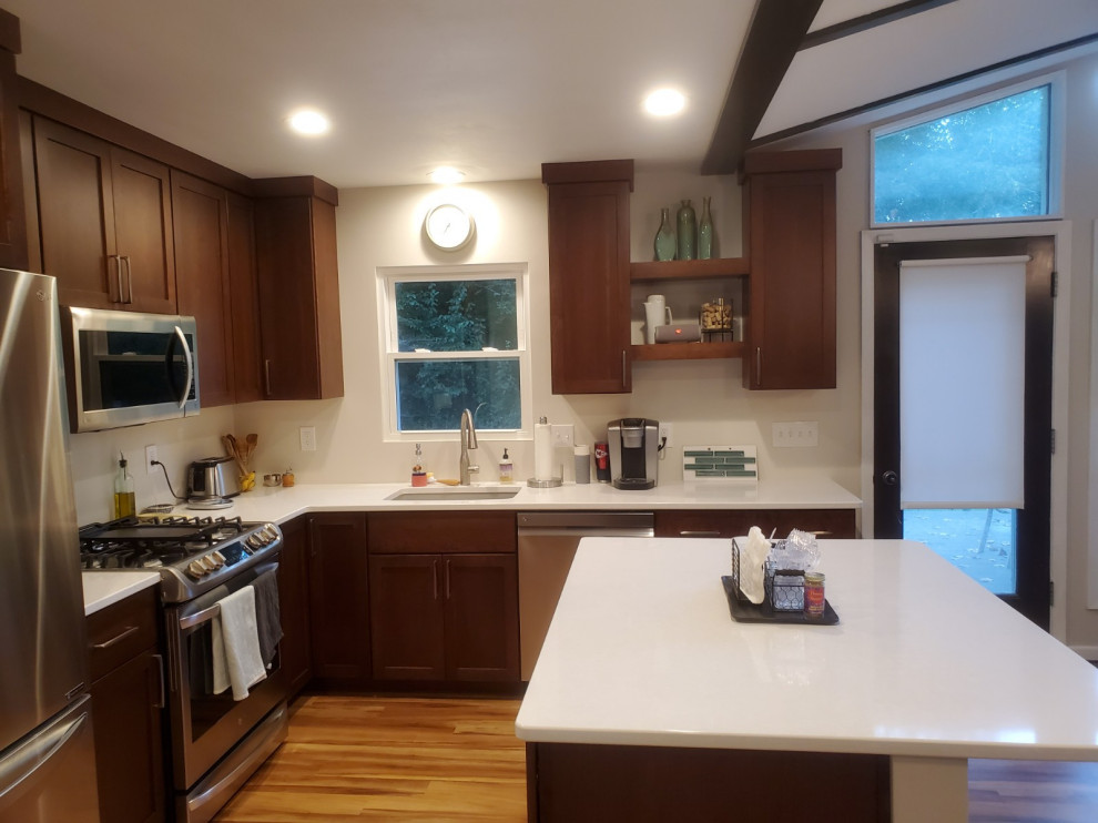 Mid-sized 1950s l-shaped brown floor eat-in kitchen photo in Other with an undermount sink, shaker cabinets, medium tone wood cabinets, stainless steel appliances, an island and white countertops