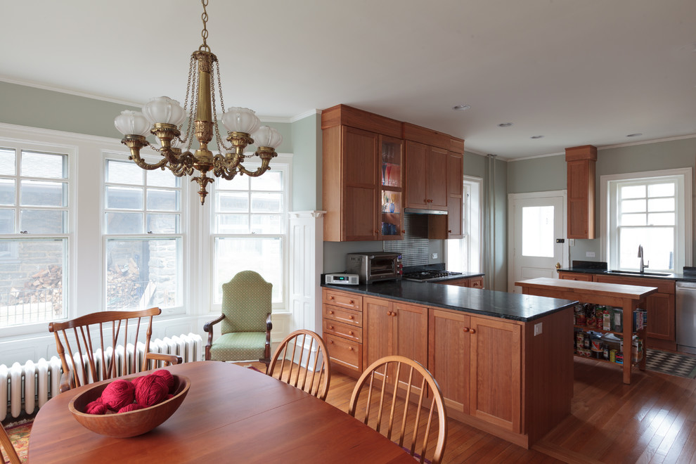 Example of a mid-sized arts and crafts u-shaped light wood floor and brown floor eat-in kitchen design in Philadelphia with an undermount sink, recessed-panel cabinets, brown cabinets, soapstone countertops, stainless steel appliances and a peninsula