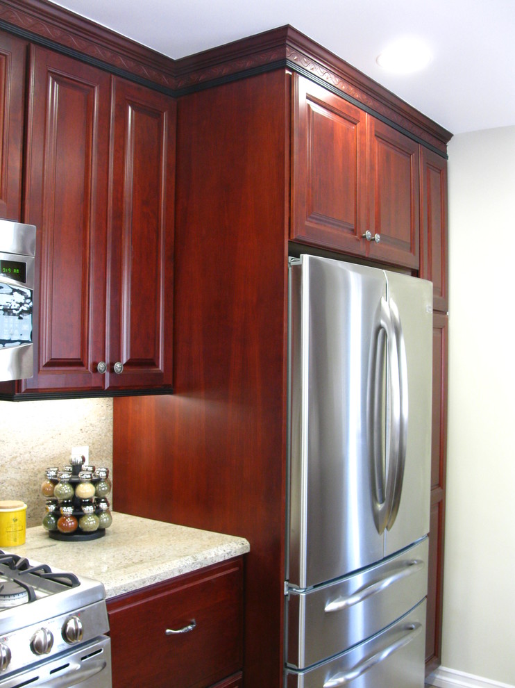 Elegant kitchen photo in Los Angeles with a peninsula, raised-panel cabinets, red cabinets and an undermount sink