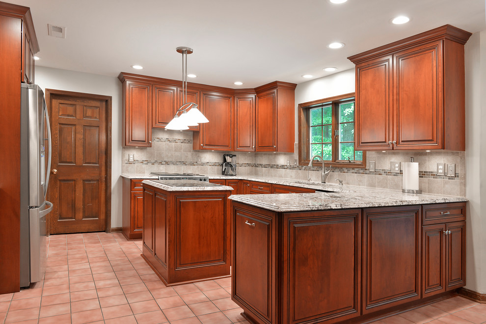 Klassisk inredning av ett mellanstort grå grått kök, med en undermonterad diskho, luckor med upphöjd panel, skåp i mellenmörkt trä, granitbänkskiva, grått stänkskydd, stänkskydd i keramik, rostfria vitvaror, klinkergolv i keramik, en köksö och rosa golv