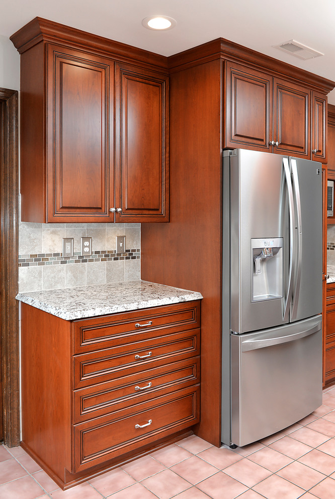 Inredning av ett klassiskt mellanstort grå grått kök, med en undermonterad diskho, luckor med upphöjd panel, skåp i mellenmörkt trä, granitbänkskiva, grått stänkskydd, stänkskydd i keramik, rostfria vitvaror, klinkergolv i keramik, en köksö och rosa golv