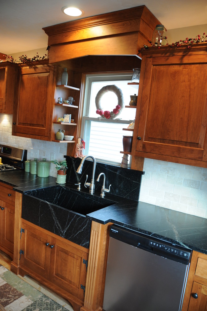 Bild på ett mellanstort lantligt kök, med en integrerad diskho, luckor med upphöjd panel, skåp i mellenmörkt trä, bänkskiva i täljsten, beige stänkskydd, stänkskydd i stenkakel, rostfria vitvaror och ljust trägolv