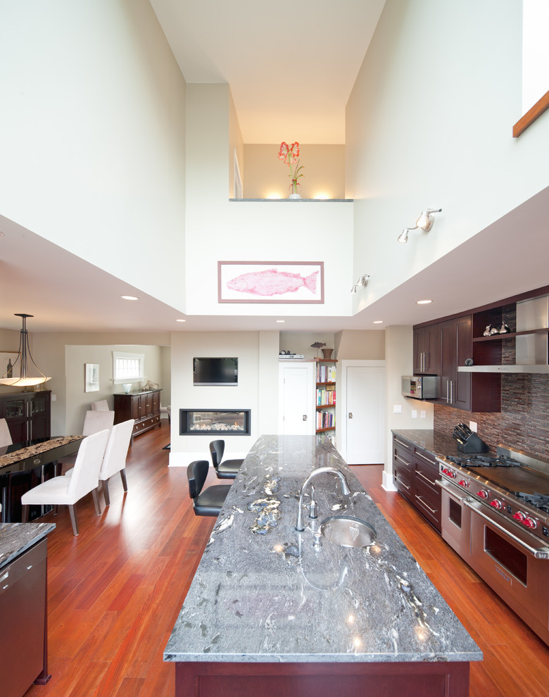 Cette image montre une cuisine minimaliste avec un placard à porte shaker, des portes de placard rouges, un électroménager en acier inoxydable et îlot.