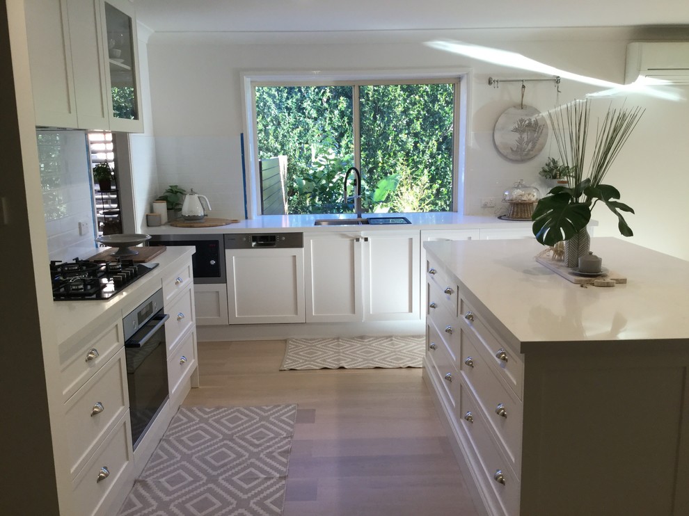 Example of a mid-sized transitional light wood floor and brown floor eat-in kitchen design in Sydney with an undermount sink, shaker cabinets, white cabinets, quartz countertops, white backsplash, subway tile backsplash, stainless steel appliances, an island and white countertops