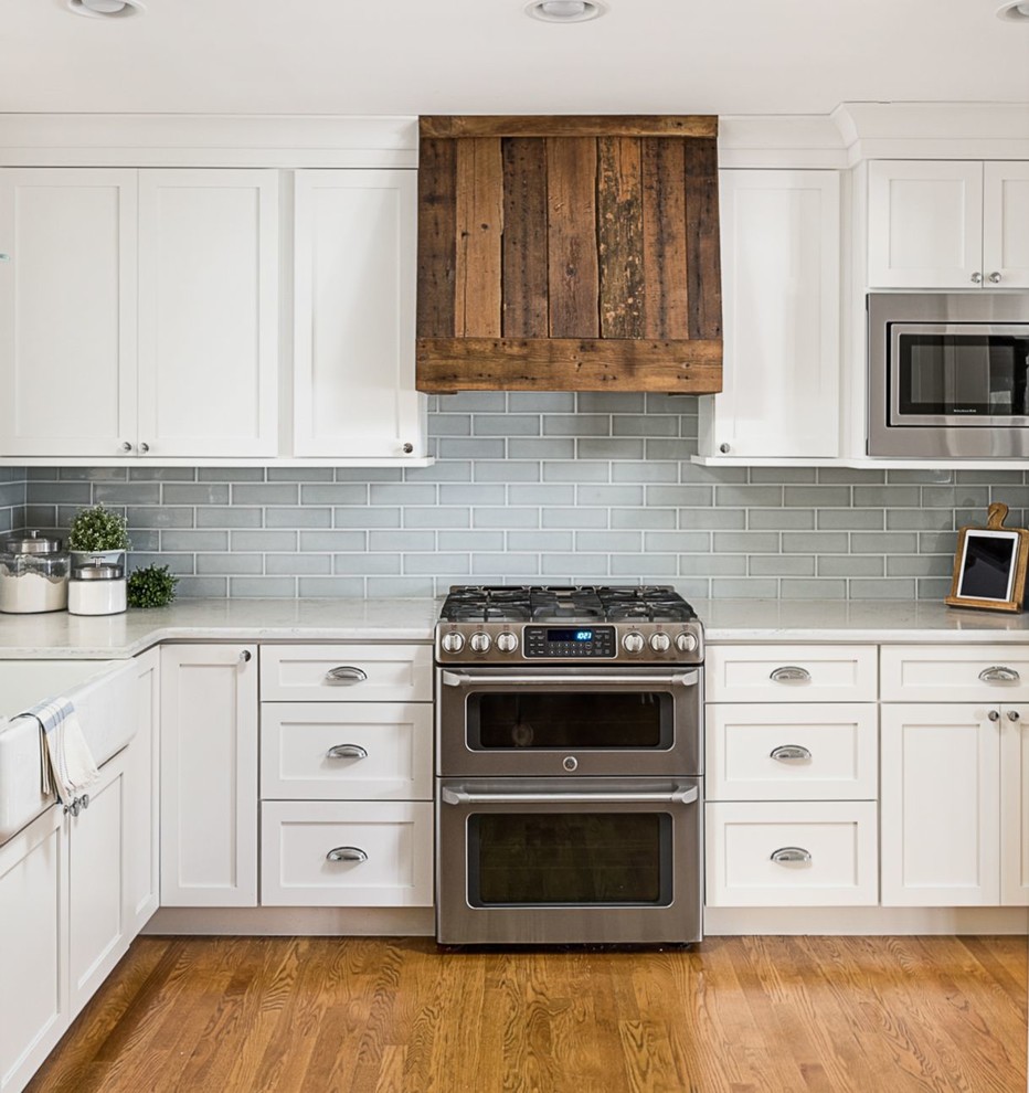 Open concept kitchen - mid-sized country l-shaped dark wood floor and brown floor open concept kitchen idea in Chicago with a farmhouse sink, shaker cabinets, white cabinets, quartz countertops, blue backsplash, porcelain backsplash, stainless steel appliances and a peninsula