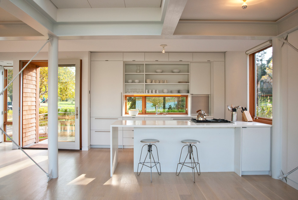 На фото: параллельная кухня в стиле модернизм с плоскими фасадами, белыми фасадами, техникой под мебельный фасад, обеденным столом и полуостровом