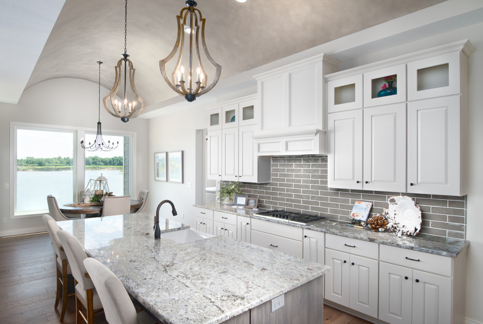 Medium sized coastal l-shaped open plan kitchen in Wichita with white cabinets, granite worktops, grey splashback, brick splashback, stainless steel appliances and an island.