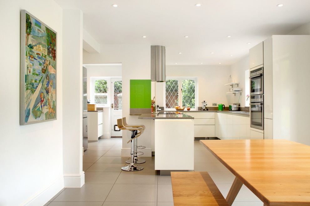 This is an example of a contemporary l-shaped open plan kitchen in Buckinghamshire with flat-panel cabinets, white cabinets and an island.