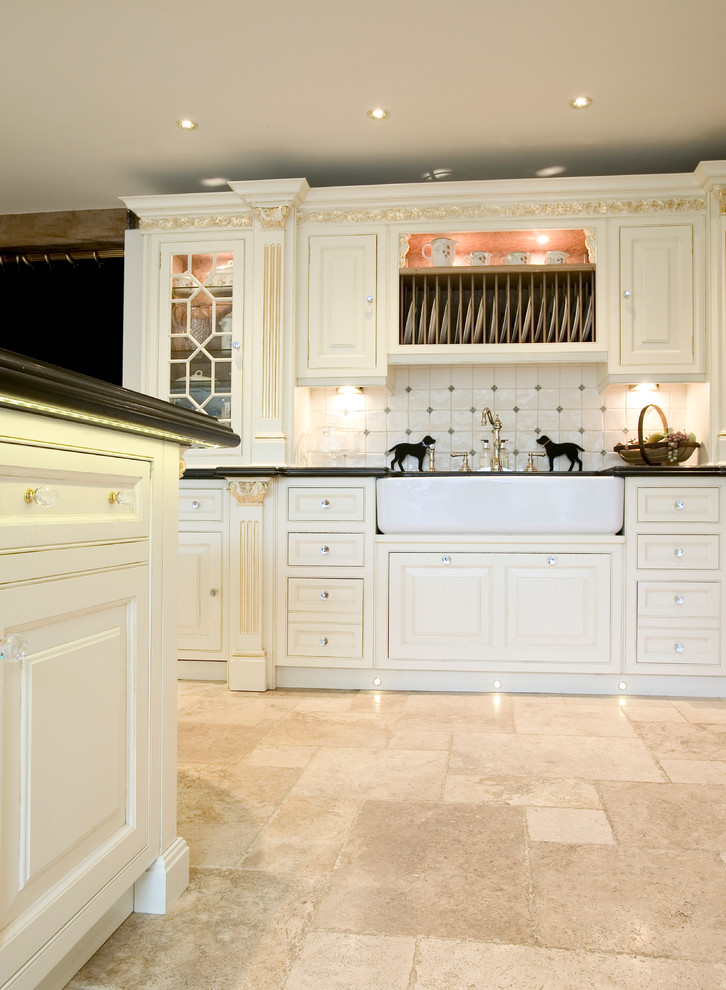 Traditional open plan kitchen in Cheshire with a belfast sink, recessed-panel cabinets, quartz worktops, ceramic splashback, black appliances and limestone flooring.