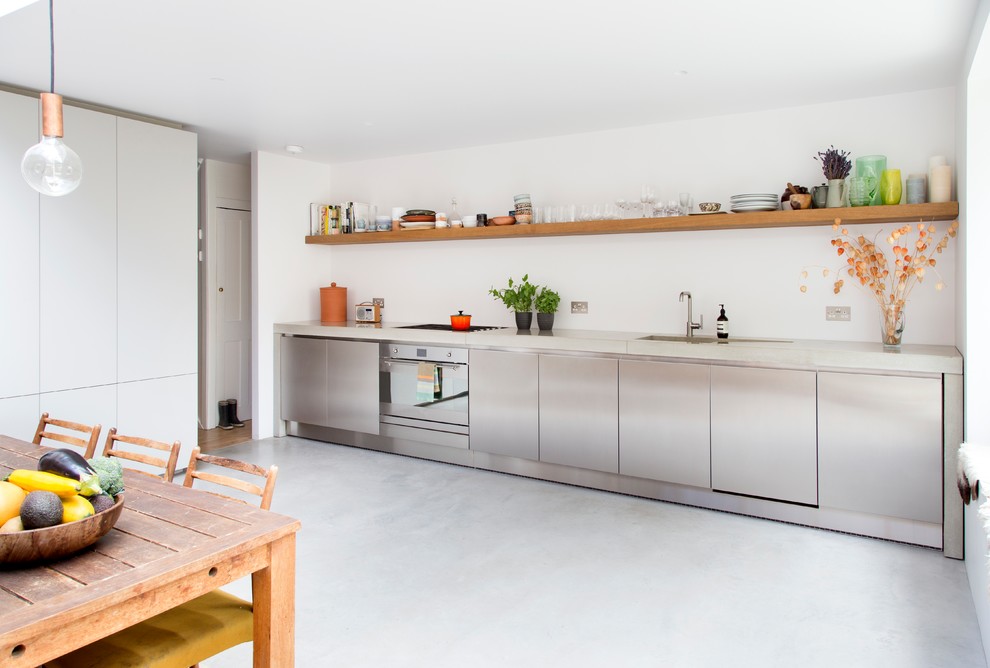 Inspiration för mellanstora moderna linjära grått kök och matrum, med en integrerad diskho, släta luckor, skåp i rostfritt stål, bänkskiva i betong, rostfria vitvaror, vitt stänkskydd och grått golv