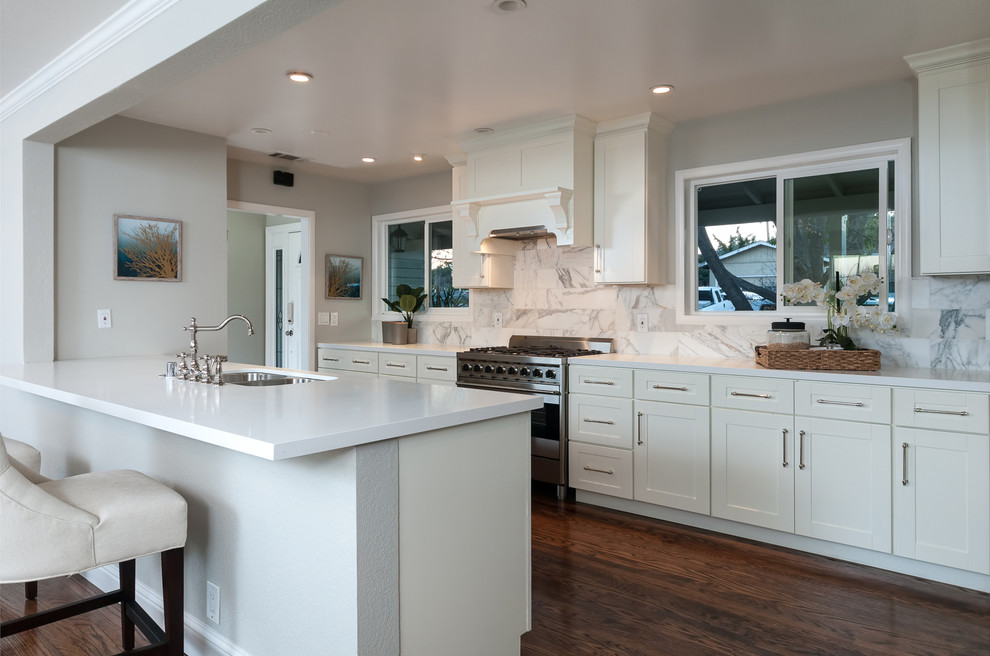 Bild på ett mellanstort funkis kök, med en dubbel diskho, skåp i shakerstil, vita skåp, bänkskiva i koppar, vitt stänkskydd, stänkskydd i marmor, rostfria vitvaror, mörkt trägolv och en köksö