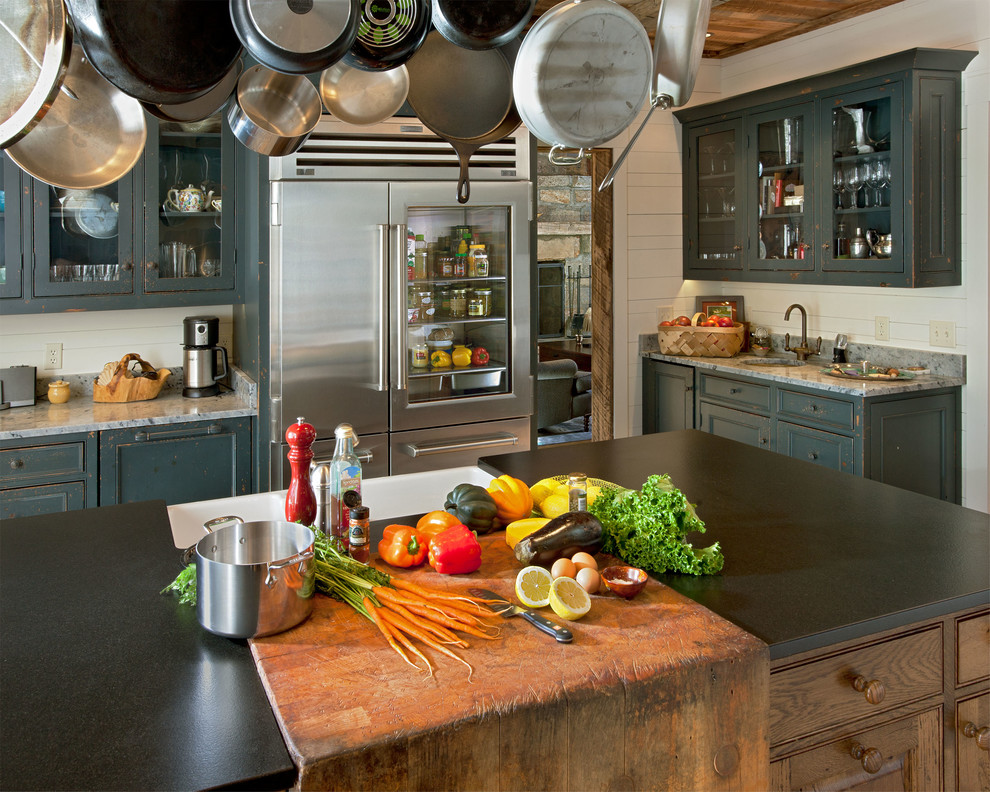 Inspiration for a rustic kitchen in Other with glass-front cabinets, a belfast sink, stainless steel appliances and distressed cabinets.