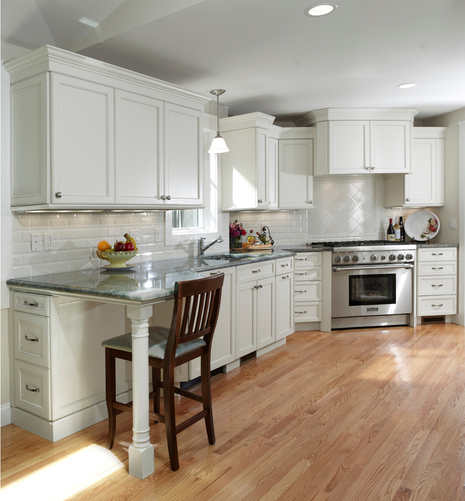 Eat-in kitchen - mid-sized traditional l-shaped light wood floor eat-in kitchen idea in Boston with an undermount sink, recessed-panel cabinets, white cabinets, granite countertops, white backsplash, subway tile backsplash, stainless steel appliances and no island