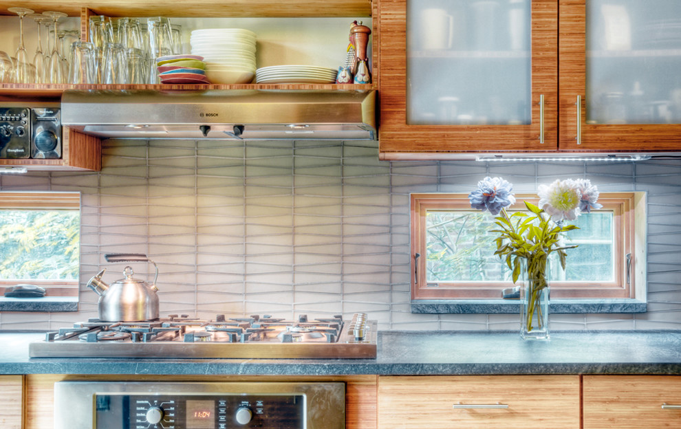 Exempel på ett modernt kök, med luckor med glaspanel, skåp i mellenmörkt trä, bänkskiva i täljsten och grått stänkskydd