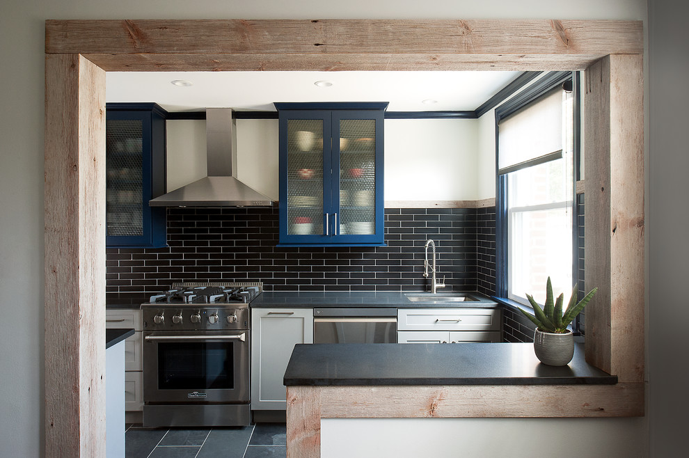 This is an example of a medium sized urban galley kitchen/diner in Philadelphia with a submerged sink, shaker cabinets, blue cabinets, granite worktops, black splashback, ceramic splashback, stainless steel appliances, slate flooring, a breakfast bar and black floors.
