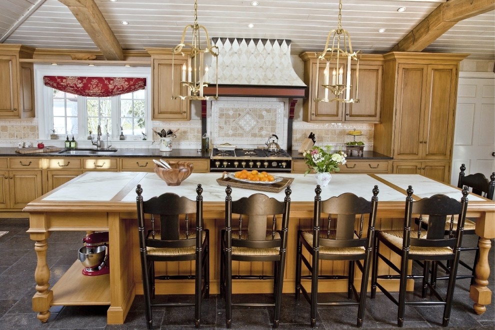 Imagen de cocina clásica con armarios con paneles con relieve, puertas de armario de madera oscura, salpicadero beige y electrodomésticos negros