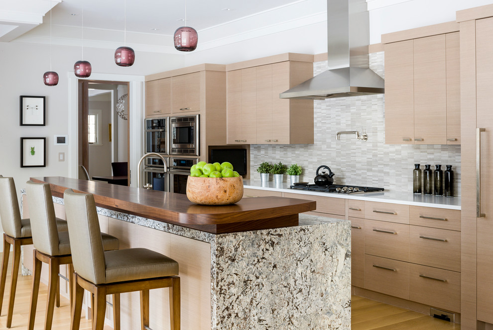 Foto på ett mellanstort funkis kök, med släta luckor, skåp i ljust trä, marmorbänkskiva, beige stänkskydd, stänkskydd i keramik, rostfria vitvaror, ljust trägolv och en köksö