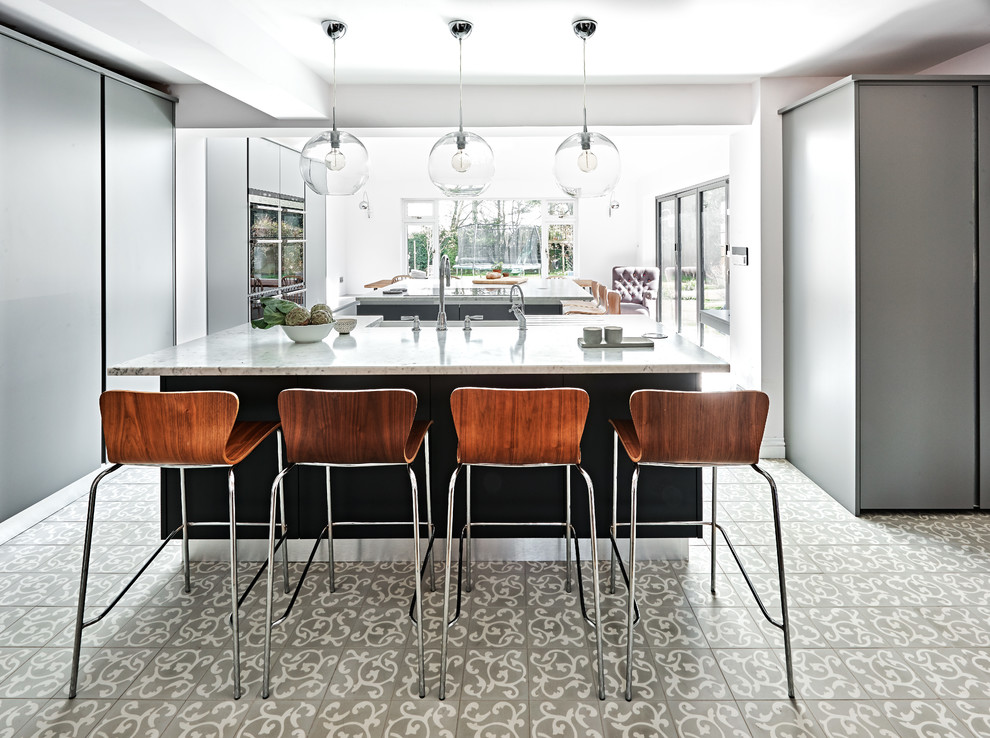 Offene Moderne Küche mit flächenbündigen Schrankfronten, grauen Schränken, zwei Kücheninseln und buntem Boden in Wiltshire