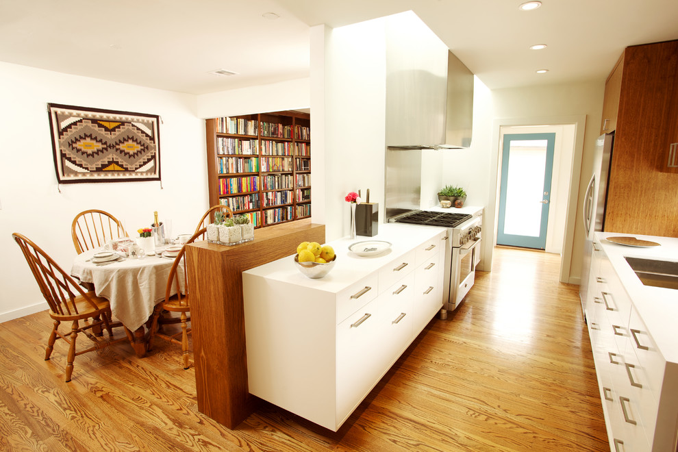 Eat-in kitchen - mid-sized contemporary galley dark wood floor and brown floor eat-in kitchen idea in Los Angeles with stainless steel appliances, a double-bowl sink, flat-panel cabinets, white cabinets, solid surface countertops and no island