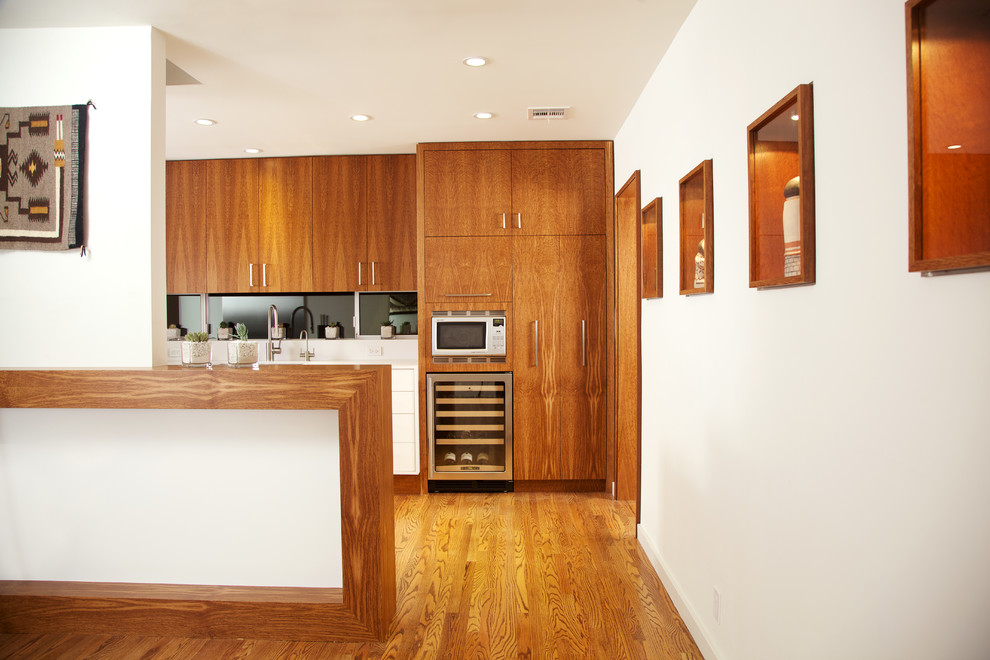 Idées déco pour une cuisine moderne en bois brun avec un placard à porte plane, un électroménager en acier inoxydable, un plan de travail en bois, une crédence noire et une crédence en feuille de verre.