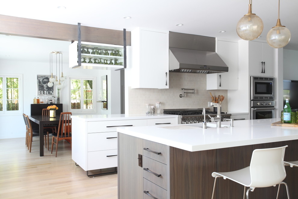 Exempel på ett modernt kök, med en undermonterad diskho, släta luckor, vita skåp, beige stänkskydd och rostfria vitvaror