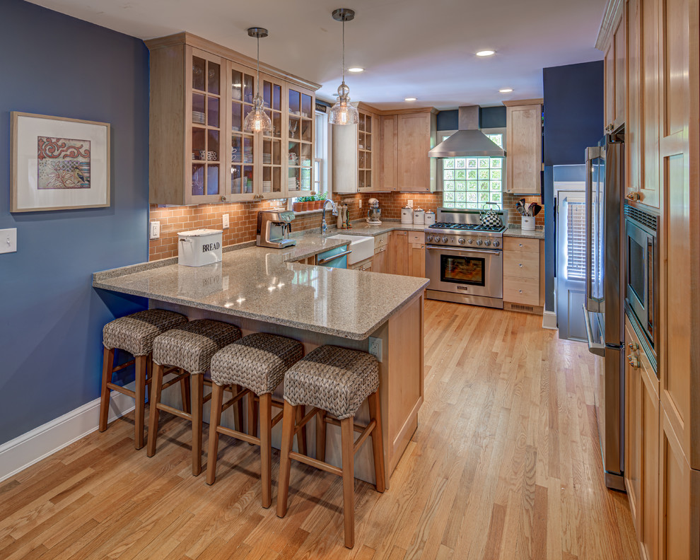 Mid-sized transitional u-shaped light wood floor and brown floor eat-in kitchen photo in DC Metro with a farmhouse sink, shaker cabinets, light wood cabinets, quartz countertops, orange backsplash, subway tile backsplash, stainless steel appliances, a peninsula and beige countertops