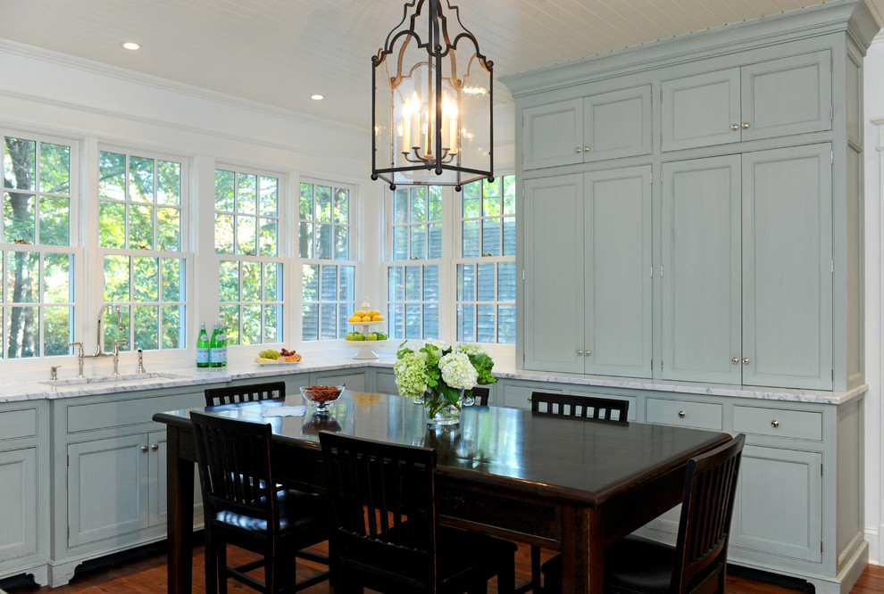 Klassisk inredning av ett stort kök, med en undermonterad diskho, skåp i shakerstil, marmorbänkskiva, vitt stänkskydd, stänkskydd i sten, rostfria vitvaror, mellanmörkt trägolv, en köksö och blå skåp