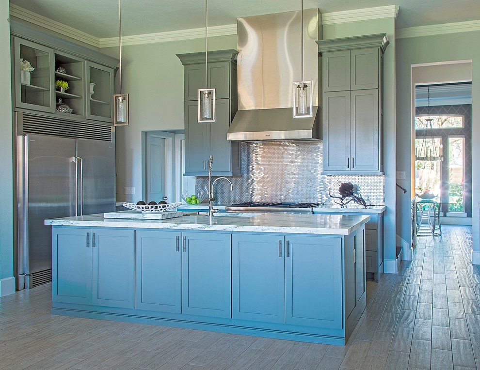Modern inredning av ett stort kök, med en undermonterad diskho, luckor med infälld panel, grå skåp, marmorbänkskiva, stänkskydd med metallisk yta, stänkskydd i metallkakel, rostfria vitvaror, en köksö och klinkergolv i porslin