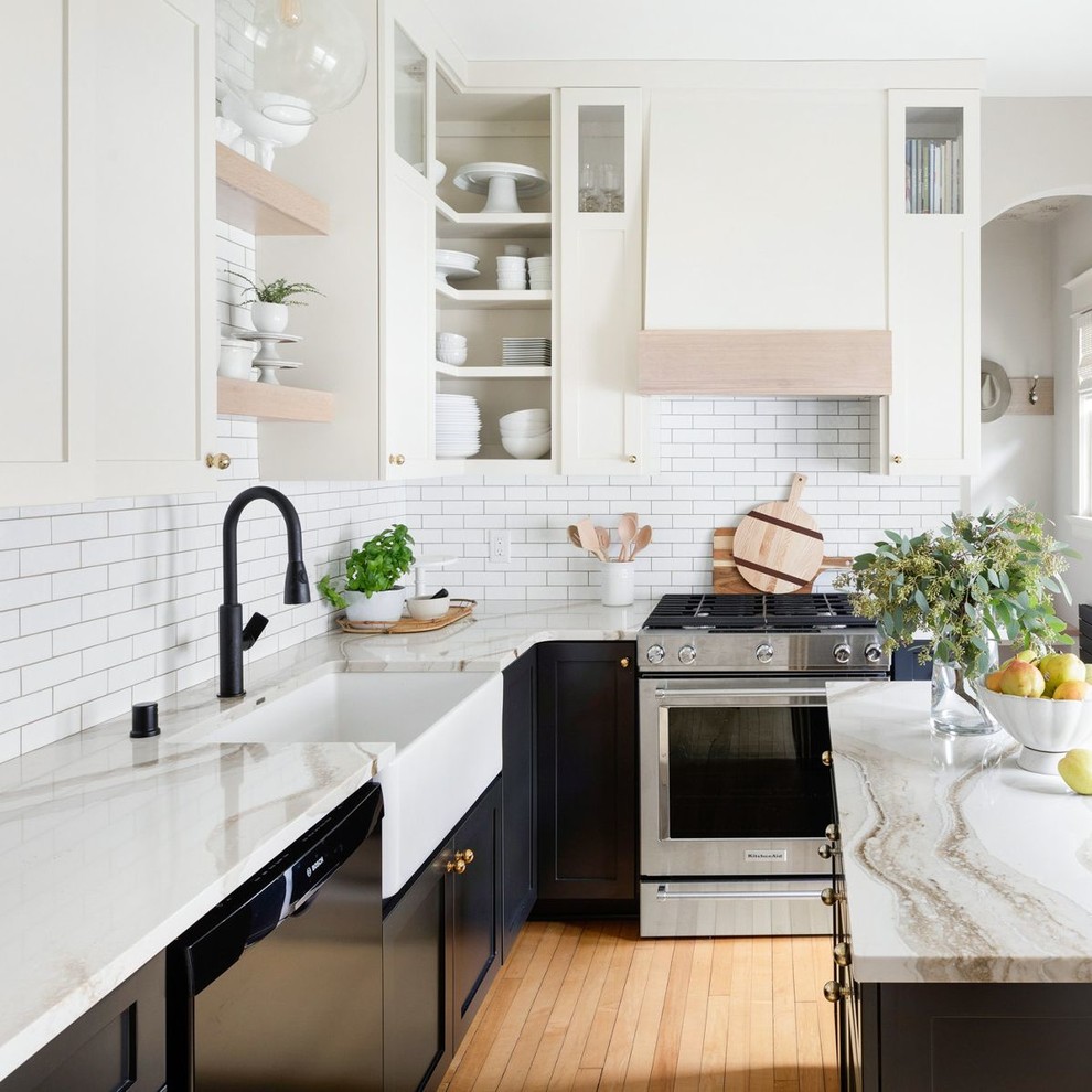 Inspiration for a traditional enclosed kitchen in Minneapolis with a belfast sink, engineered stone countertops, white splashback, metro tiled splashback, stainless steel appliances, light hardwood flooring and an island.