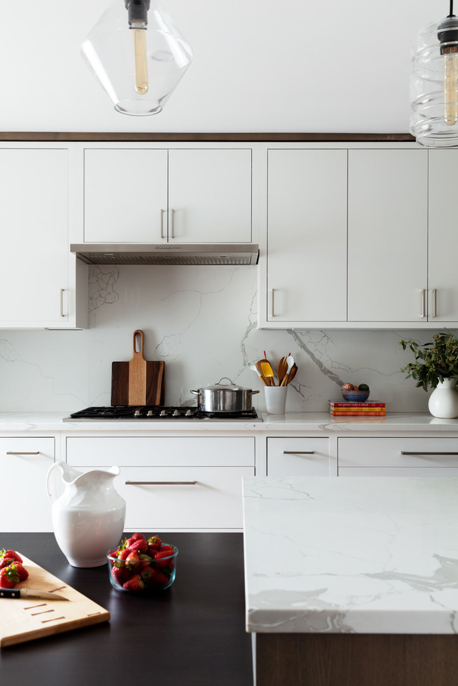 Idéer för mellanstora funkis linjära vitt kök med öppen planlösning, med släta luckor, skåp i ljust trä, bänkskiva i kvarts, vitt stänkskydd, stänkskydd i marmor, rostfria vitvaror, ljust trägolv, en köksö och beiget golv