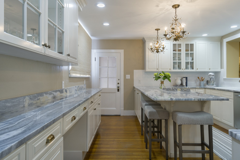 Small cottage chic u-shaped medium tone wood floor kitchen photo in Tampa with a drop-in sink, raised-panel cabinets, white cabinets, marble countertops, white backsplash, ceramic backsplash, white appliances and no island
