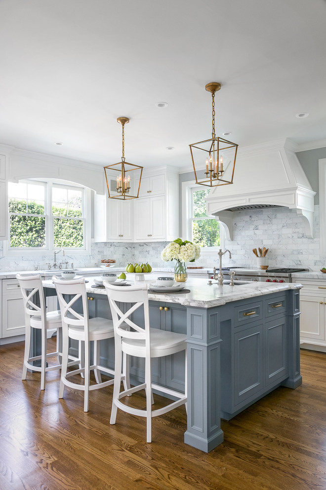 Example of a classic l-shaped dark wood floor and brown floor kitchen design in San Francisco with an undermount sink, recessed-panel cabinets, gray cabinets, white backsplash, marble backsplash, stainless steel appliances and an island