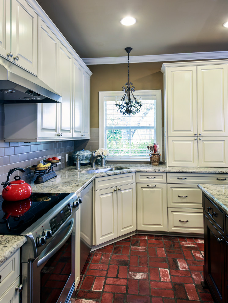 Idéer för att renovera ett stort vintage kök, med en undermonterad diskho, luckor med upphöjd panel, vita skåp, granitbänkskiva, beige stänkskydd, stänkskydd i glaskakel, rostfria vitvaror, tegelgolv och en köksö