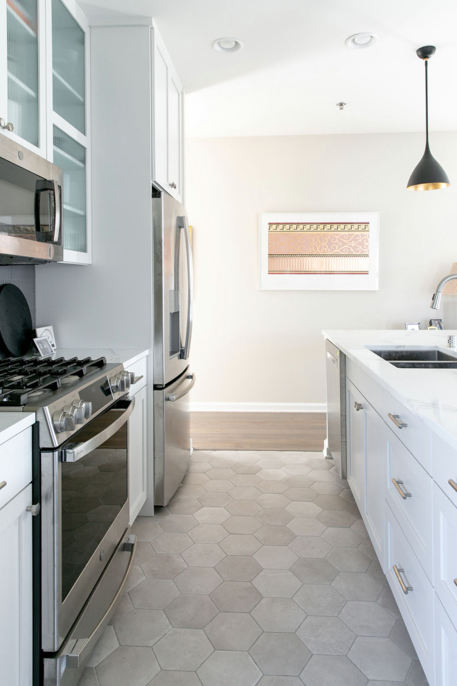 Photo of a small contemporary galley kitchen/diner in New York with a submerged sink, glass-front cabinets, white cabinets, engineered stone countertops, grey splashback, glass tiled splashback, stainless steel appliances, porcelain flooring, an island, grey floors and white worktops.