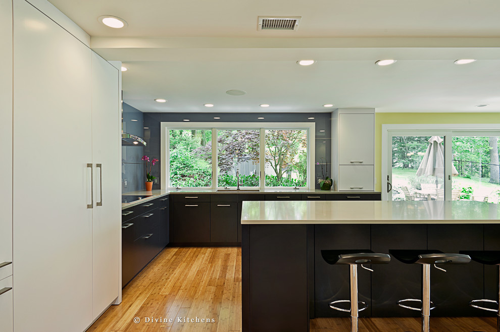 Example of a large trendy u-shaped light wood floor eat-in kitchen design in Boston with an undermount sink, flat-panel cabinets, white cabinets, quartz countertops, gray backsplash, glass sheet backsplash, stainless steel appliances and an island