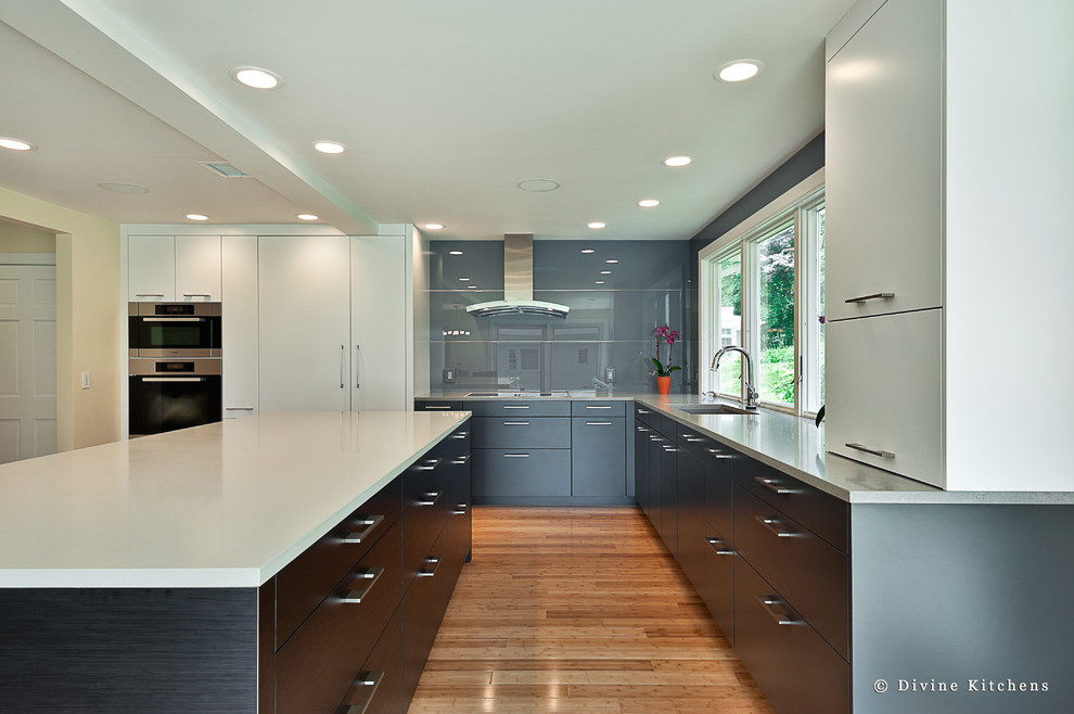 This is an example of a large contemporary u-shaped kitchen/diner in Boston with a submerged sink, flat-panel cabinets, white cabinets, engineered stone countertops, grey splashback, glass sheet splashback, stainless steel appliances, light hardwood flooring and an island.