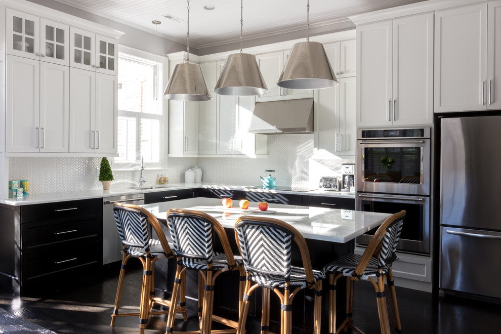 Inredning av ett klassiskt kök, med en undermonterad diskho, skåp i shakerstil, vita skåp, bänkskiva i kvarts, vitt stänkskydd, stänkskydd i mosaik, rostfria vitvaror, mörkt trägolv, en köksö och brunt golv