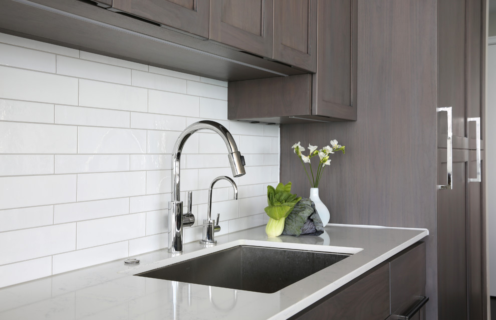 Eat-in kitchen - small modern galley eat-in kitchen idea in Chicago with an undermount sink, flat-panel cabinets, medium tone wood cabinets, quartz countertops, white backsplash, porcelain backsplash, paneled appliances and no island