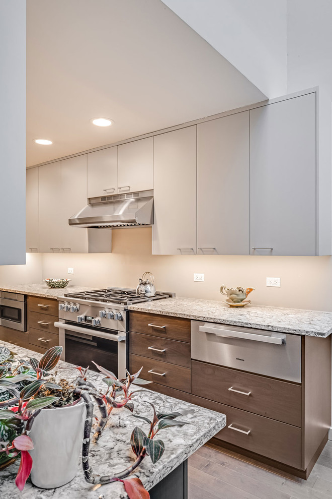 Inspiration for a mid-sized contemporary galley medium tone wood floor and brown floor enclosed kitchen remodel in Chicago with an undermount sink, flat-panel cabinets, white cabinets, white backsplash, stainless steel appliances, no island and gray countertops