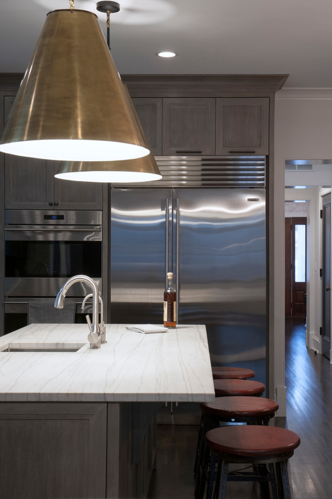 Foto på ett mellanstort funkis kök, med en nedsänkt diskho, luckor med infälld panel, skåp i slitet trä, marmorbänkskiva, rostfria vitvaror, mörkt trägolv och en köksö