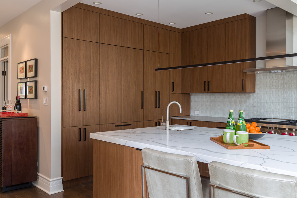 Photo of a medium sized contemporary u-shaped kitchen/diner in Chicago with a single-bowl sink, flat-panel cabinets, light wood cabinets, engineered stone countertops, white splashback, glass tiled splashback, stainless steel appliances, dark hardwood flooring and an island.
