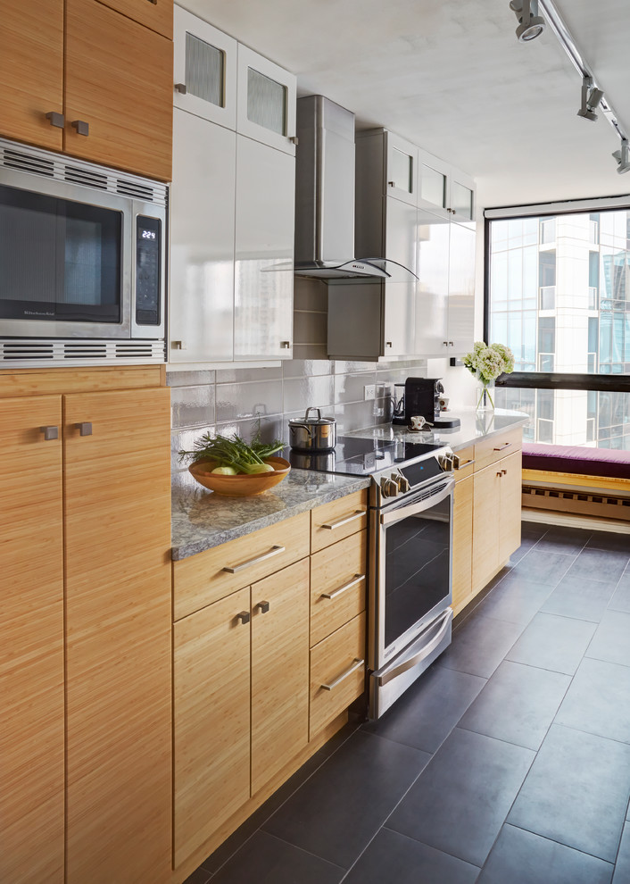 Photo of a small modern galley enclosed kitchen in Chicago with a double-bowl sink, flat-panel cabinets, white cabinets, engineered stone countertops, grey splashback, glass tiled splashback, stainless steel appliances, porcelain flooring and a breakfast bar.